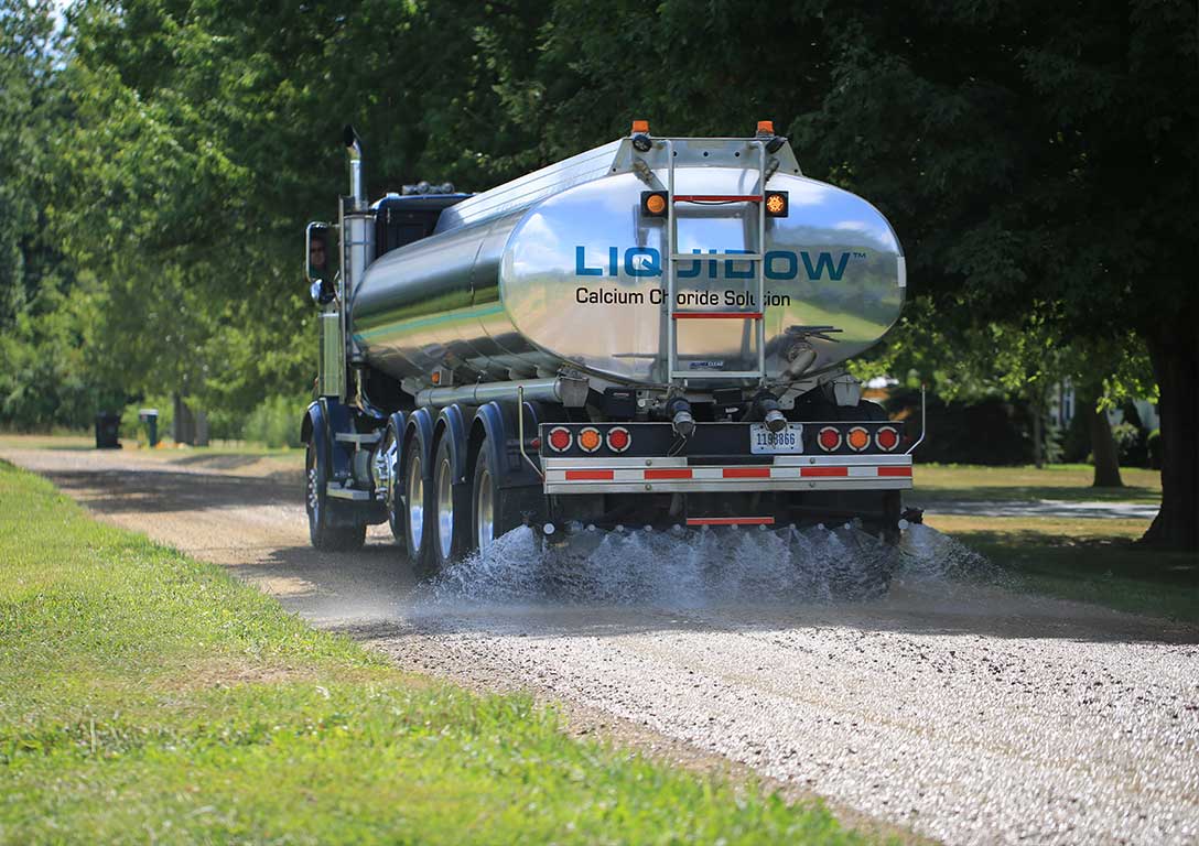 tanker spraying LIQUIDOW on gravel road - roads: dust control - OxyChem calcium chloride